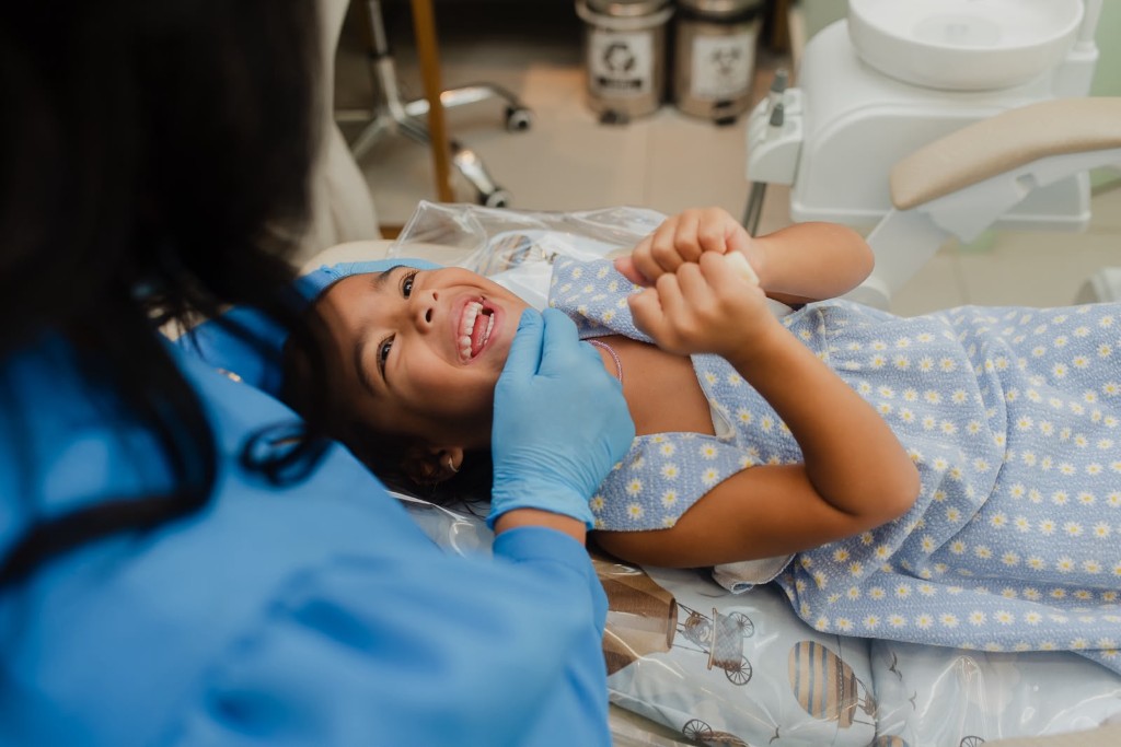 Criança sorrindo durante consulta odontopediátrica na Clínica Evident